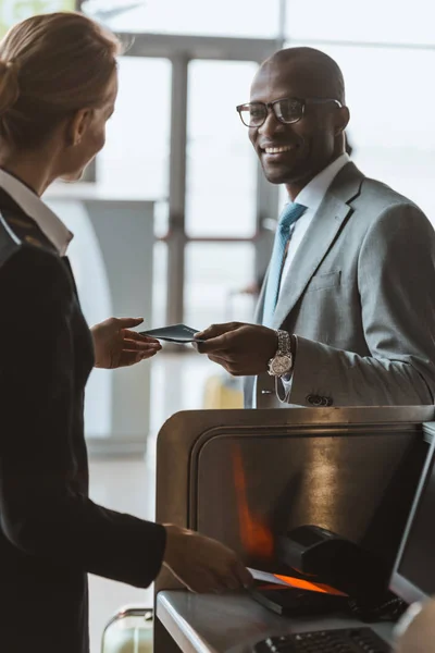 Lächelnder gutaussehender Geschäftsmann gibt Mitarbeitern am Flughafen-Check-in-Schalter Pass — Stockfoto