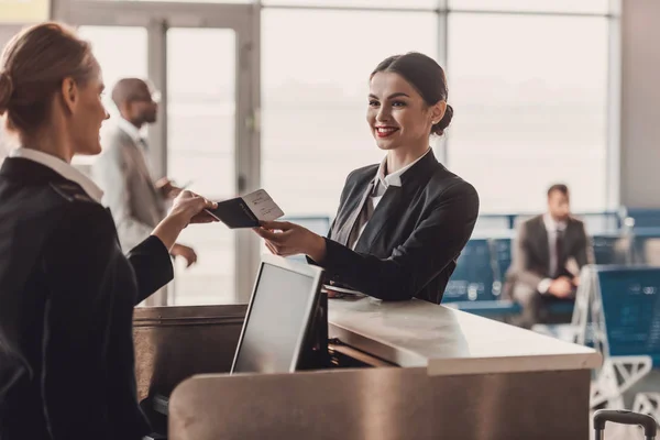 Glückliche Geschäftsfrau gibt Pass und Ticket an Mitarbeiter am Flughafen-Check-in-Schalter — Stockfoto