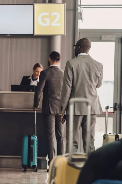 Vista trasera de la cola de empresarios en el mostrador de facturación del aeropuerto - foto de stock