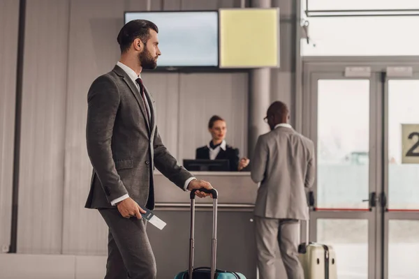 Homem de negócios com bagagem e bilhete de avião no aeroporto — Fotografia de Stock