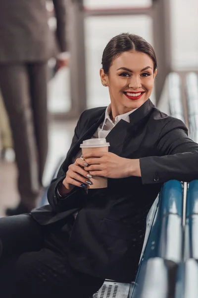 Jovem empresária à espera de avião no aeroporto e tendo xícara de café para ir — Fotografia de Stock