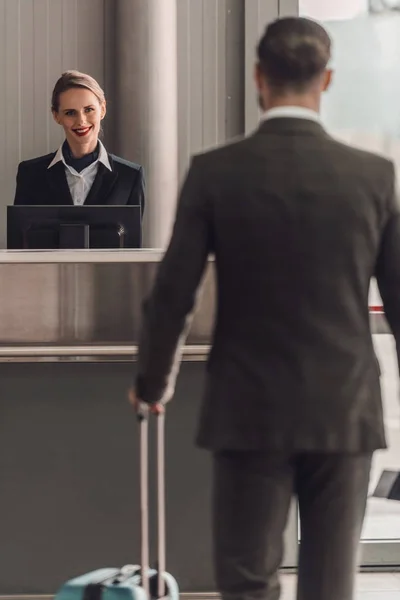 Vista trasera del hombre de negocios caminando al mostrador de facturación del aeropuerto - foto de stock