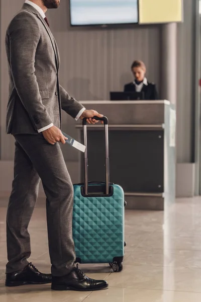 Vista trasera del hombre de negocios con maleta delante del mostrador de facturación del aeropuerto — Stock Photo