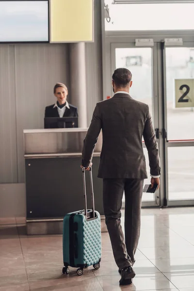 Rückansicht eines Geschäftsmannes, der zum Flughafen-Check-in-Schalter läuft — Stockfoto