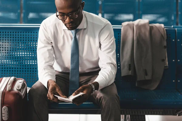 Бизнесмен читает книгу в ожидании рейса в вестибюле аэропорта — стоковое фото