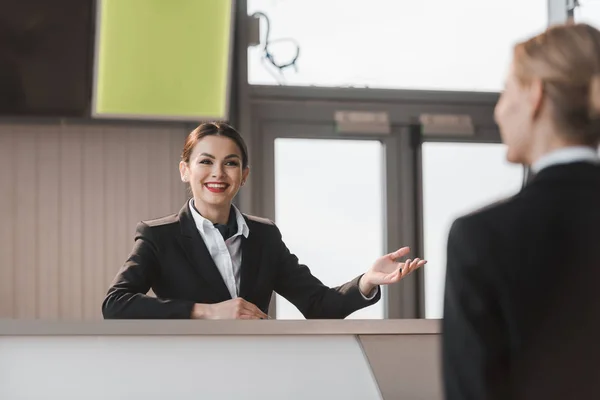 Sonriente atractiva recepcionista del aeropuerto hablando con el cliente - foto de stock