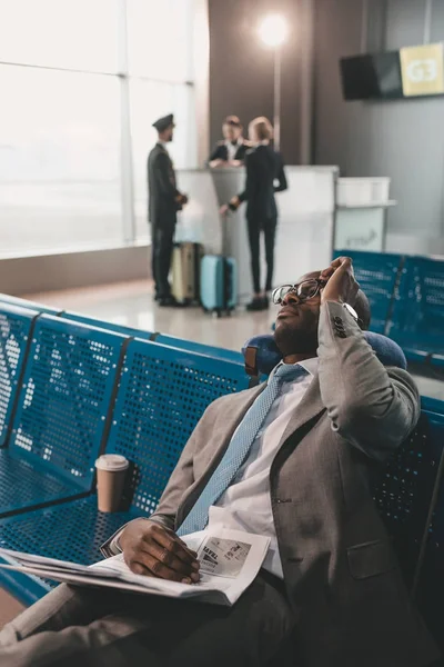 Бизнесмен спит в вестибюле аэропорта в ожидании рейса — стоковое фото