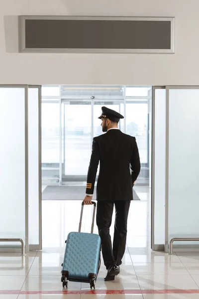 Rückansicht junger Pilot mit Koffer im Abflugbereich — Stockfoto