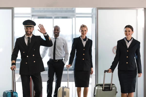 Young aviation personnel team with suitcases at airport after flight — Stock Photo