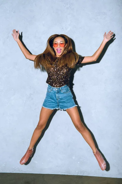 Excited young african american woman jumping and smiling on grey — Stock Photo