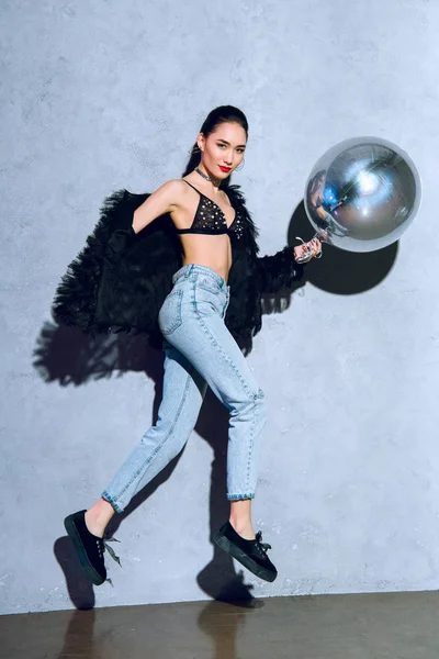 Moda joven asiático mujer holding plata globo y saltar en gris - foto de stock