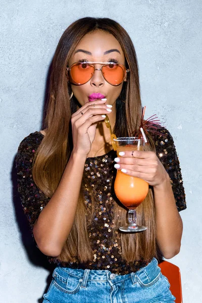 Bela menina americana africana elegante beber coquetel e olhando para a câmera — Fotografia de Stock