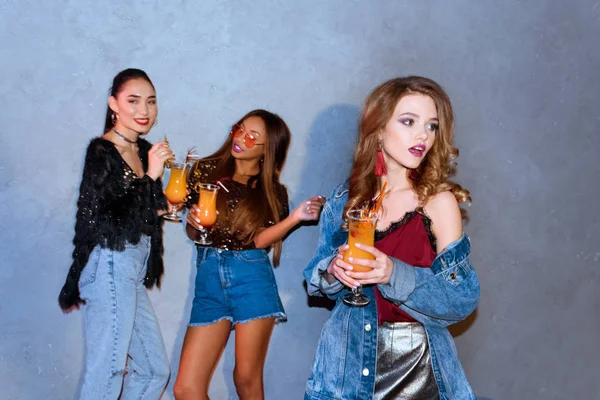 Stylish young multi ethnic women holding glasses with cocktails at party — Stock Photo