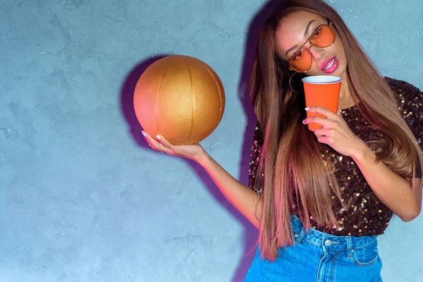 Portrait of african american woman with disposable cup and golden basketball ball — Stock Photo