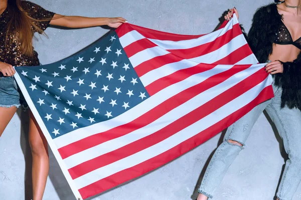 Partial view of women holding american flag in hands against concrete wall — Stock Photo