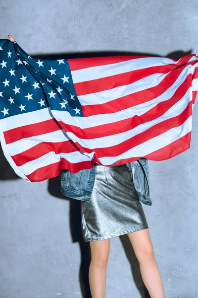 Partial view of woman holding american flag against concrete wall — Stock Photo