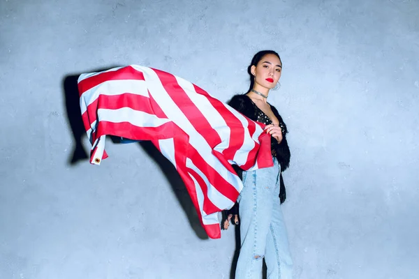 Retrato de hermosa mujer asiática con bandera americana contra pared de hormigón — Stock Photo
