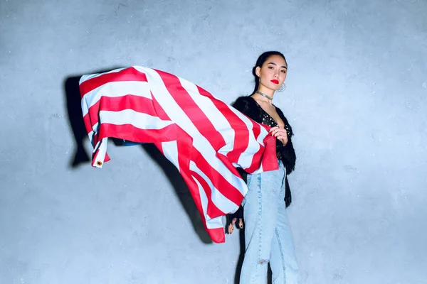 Portrait de belle femme asiatique avec drapeau américain contre mur en béton — Photo de stock