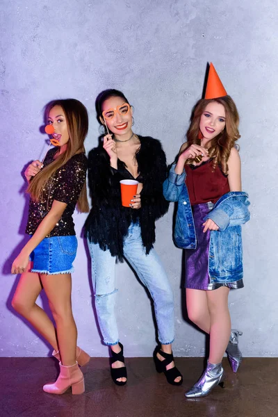 Happy multiethnic young women with party decorations against concrete wall — Stock Photo