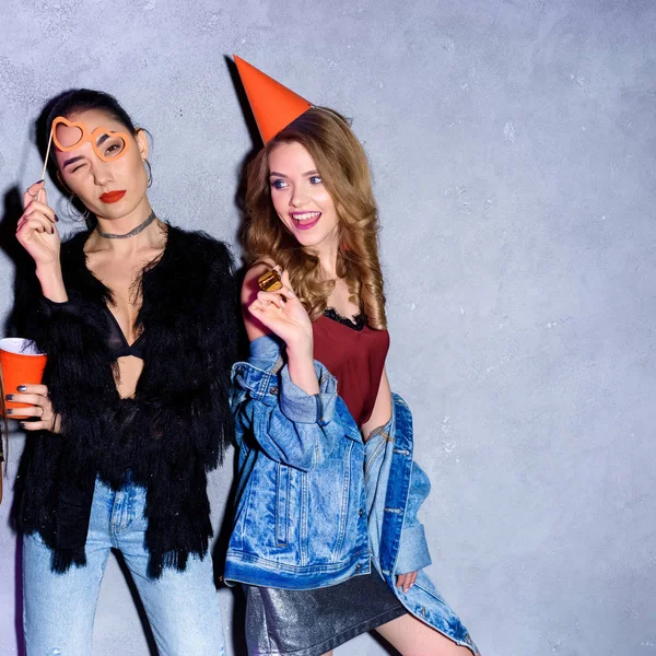 Portrait de femmes multiculturelles élégantes avec des décorations de fête contre un mur en béton — Photo de stock