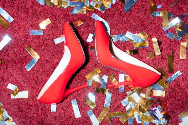 Vista superior de par de zapatos femeninos rojos en el piso con confeti - foto de stock