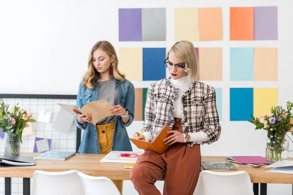Красиві редактори журналів роблять папери в сучасному офісі з кольоровою палітрою — стокове фото