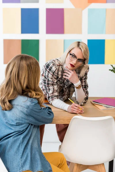 Éditeurs de magazines à la mode faisant de la paperasserie au bureau avec palette de couleurs sur le mur — Photo de stock