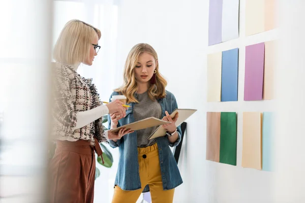 Fashionable magazine editors working with documents at color palette on wall — Stock Photo
