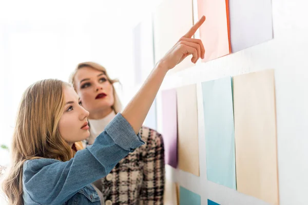 Beautiful fashionable magazine editors pointing at color palette — Stock Photo