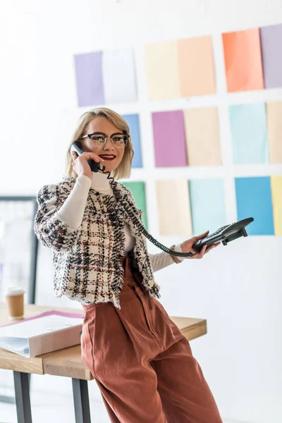 Mujer de negocios hablando por teléfono en la oficina moderna con paleta de colores en la pared - foto de stock