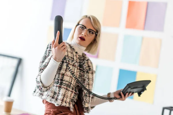 Confusion en regardant le téléphone dans le bureau moderne avec palette de couleurs sur le mur — Photo de stock