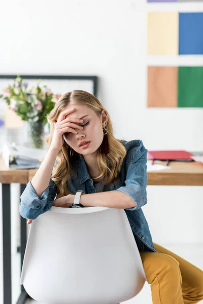 Exhausted magazine editor sitting at workplace in modern office — Stock Photo