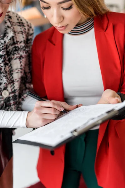 Asian magazine editors working with documents on clipboard in modern office — Stock Photo