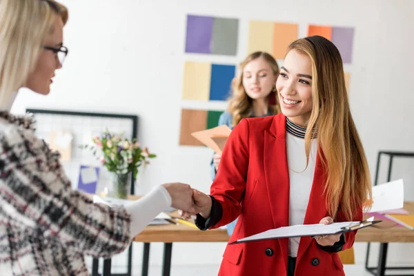 Redakteure multiethnischer Magazine beim Händeschütteln in modernen Büros — Stockfoto