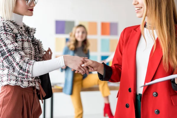 Fashionable magazine editors shaking hands in modern office — Stock Photo