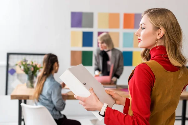 Fashionable magazine editor with folder, and colleagues working in modern office — Stock Photo