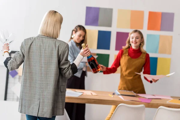 Happy magazine editors celebrating with champagne in modern office — Stock Photo