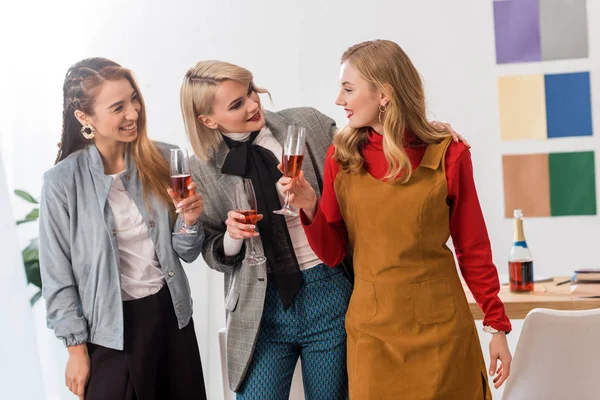 Editores de revistas multiétnicas felices celebrando con champán en la oficina moderna - foto de stock