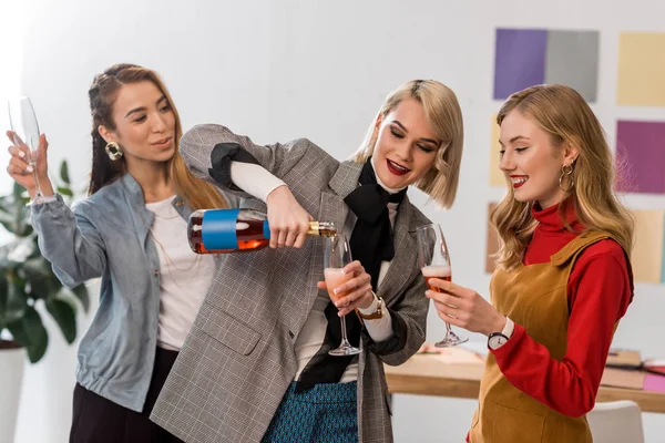 Editores de revistas multiétnicas de sucesso celebrando com champanhe no escritório moderno — Fotografia de Stock