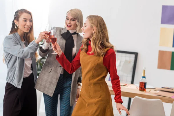 Successful magazine editors clinking with champagne glasses in modern office — Stock Photo