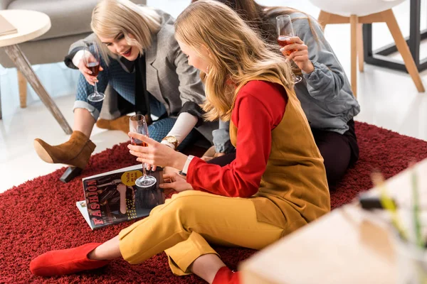 Successful businesswomen celebrating with champagne and looking at magazine in modern office — Stock Photo