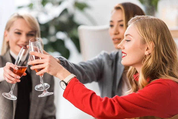 Successful fashionable businesspeople clinking with champagne glasses in modern office — Stock Photo