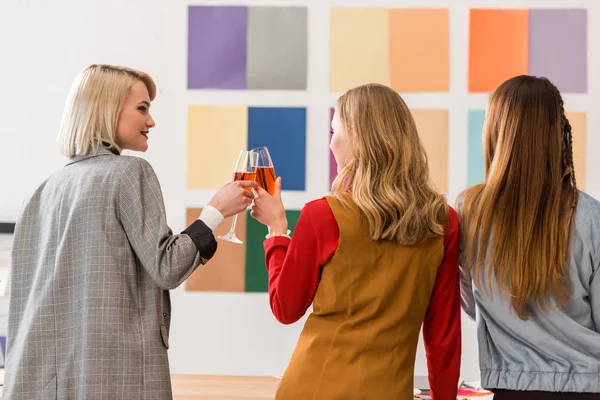 Successful magazine editors celebrating and clinking with champagne glasses in modern office — Stock Photo