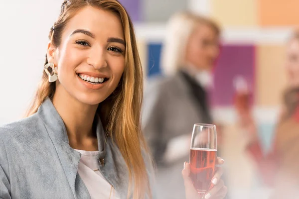 Cheerful asian girl celebrating with glass of champagne in modern office — Stock Photo