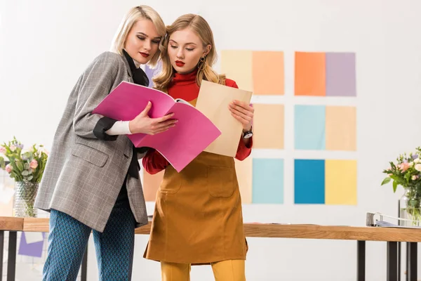 Éditeurs de magazines à la mode travaillant avec des documents dans un bureau moderne avec palette de couleurs sur le mur — Photo de stock