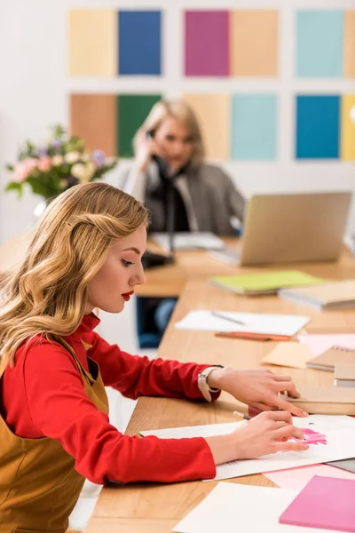 Fashion magazine editors working with sketches and laptop in modern office — Stock Photo