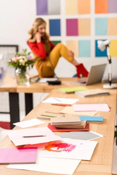 Foco seletivo do designer de moda trabalhando no escritório moderno, papelada em primeiro plano — Fotografia de Stock