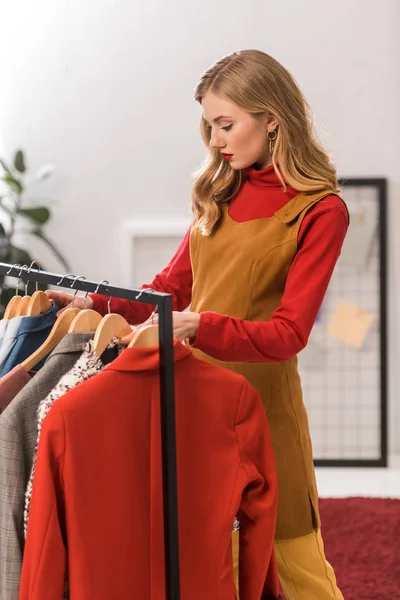 Attraktive Modedesignerin, die mit Kleidung im modernen Büro arbeitet — Stockfoto