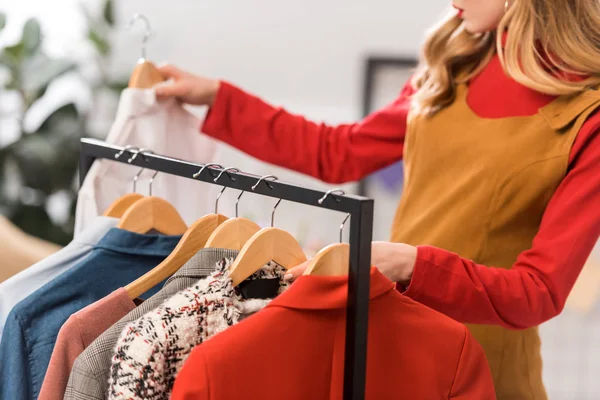 Vista recortada del diseñador de moda que trabaja con ropa en la oficina moderna - foto de stock