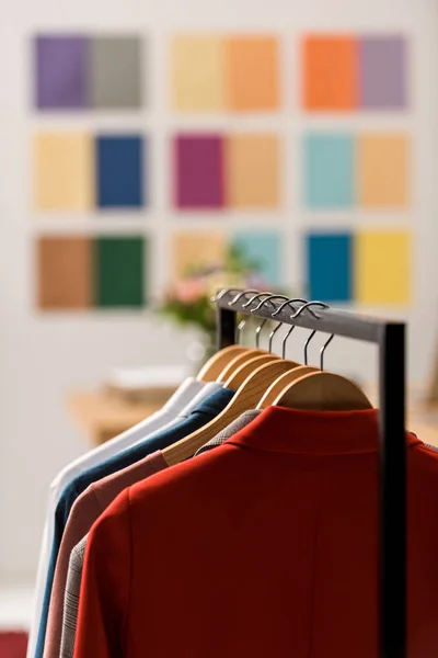 Fashionable clothes on hangers in modern office — Stock Photo